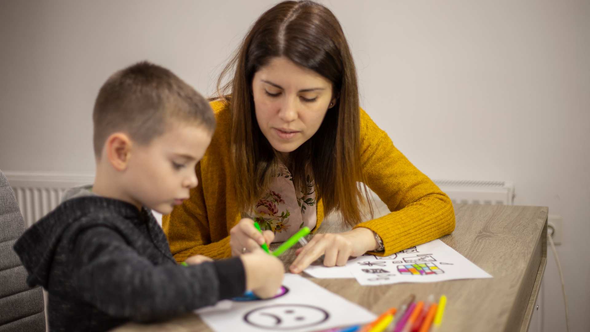 A child working with a clinician on a drawing activity as part of the ADOS-2 test