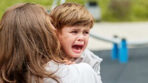 Adult comforting an upset child to represent moments of autism challenging behaviors