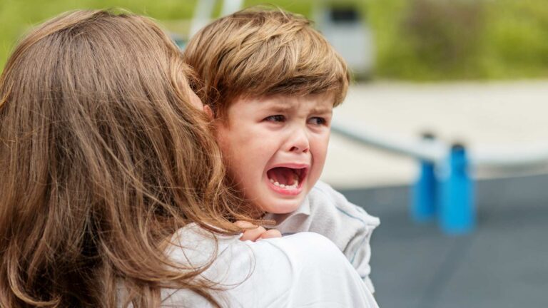 Adult comforting an upset child to represent moments of autism challenging behaviors